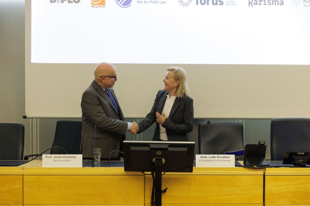 Prof. Jovan Kurbalija and Amb. Lotte Knudson shaking hands at the launch session of the CADE project, on 31 May 2024